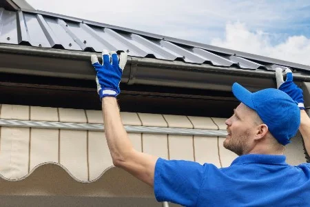 Person bringt Dachrinne an